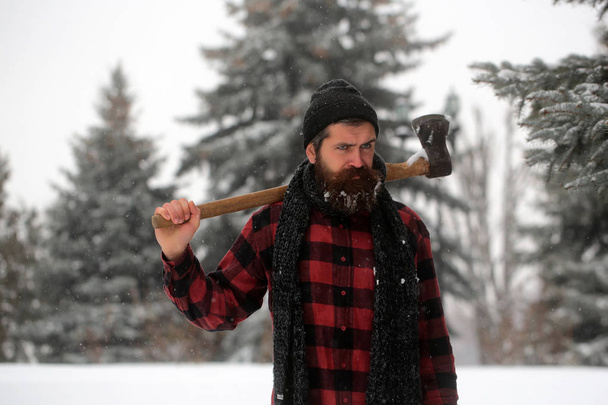 Christmas hipster lumberjack with ax in wood.. - Zdjęcie, obraz
