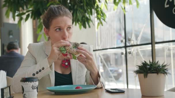 Молодая леди ест бутерброд в кафе
 - Кадры, видео