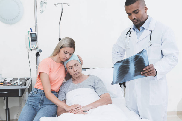 kam eine Frau zu ihrer krebskranken Mutter. die Ärztin hält ihr Röntgenbild in der Hand. - Foto, Bild