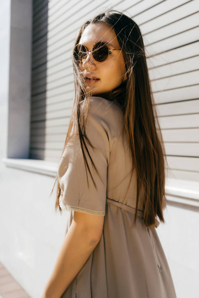 attractive young girl with long hair wearing sunglasses posing in the sun - Foto, imagen