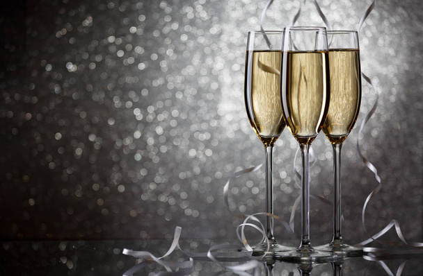 Nieuwe jaar foto van drie wijnglazen met sprankelende champagne met witte linten - Foto, afbeelding
