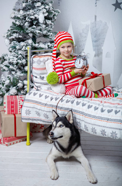 Happy cute little girl dressed in striped pajamas sitting in decorated New Year room at home. - Foto, Bild