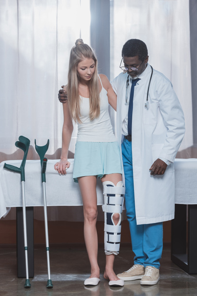 Doctor helping patient stand up  - Foto, Imagen