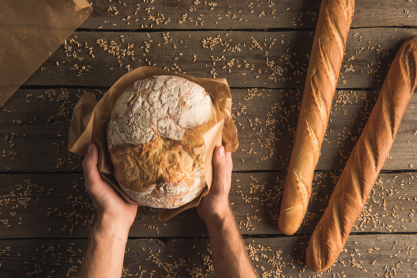 loaf of bread in hands and baguettes - Fotó, kép