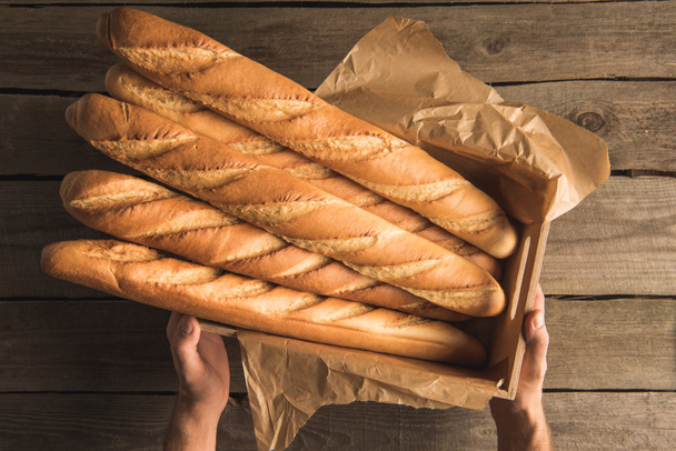 hands holding box with baguettes - Photo, Image