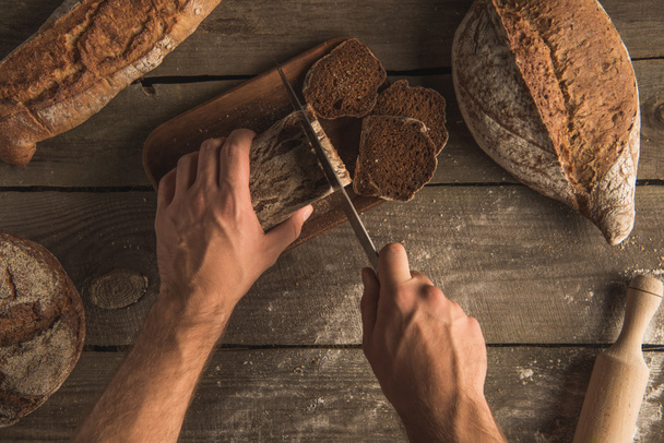 person cutting loaf of bread  - Fotó, kép