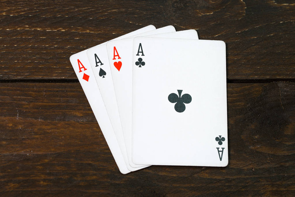 Casino-Kartenspiele spielen auf der braunen rauen Grunge-Textur von Holztisch oder Schreibtisch Vintage Farbe dunkel Ton Stil Ansicht von oben, Bande von vier Assen, Clubs oben. Poker mit vier Assen. - Foto, Bild