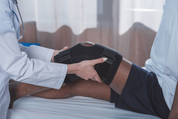 doctor putting on knee brace - Фото, изображение