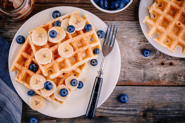 Fresh homemade belgian waffles with blueberries and banana for breakfast  - Fotó, kép