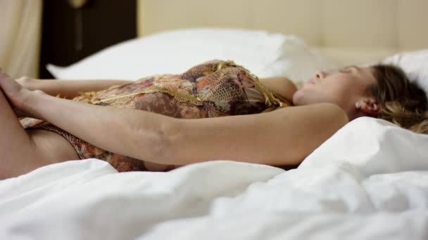Jonge prachtige vrouw die zich voordeed op bed in nachtkleding shirt met veters - Video