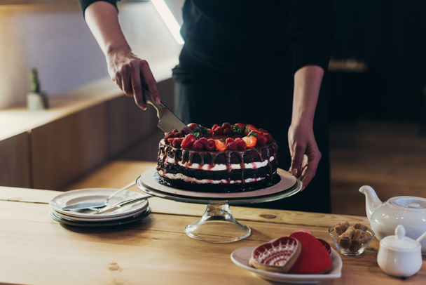 женщина режет шоколадный торт
 - Фото, изображение