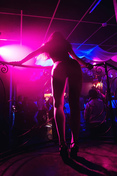 slender young girl dancer with hot body and long legs and a beautiful bend on long heels in night club - Foto, Imagem