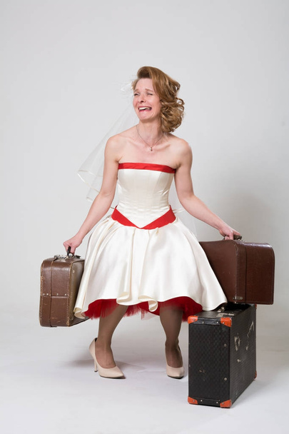Depressive bride with suitcases on a white background in the studio - Φωτογραφία, εικόνα