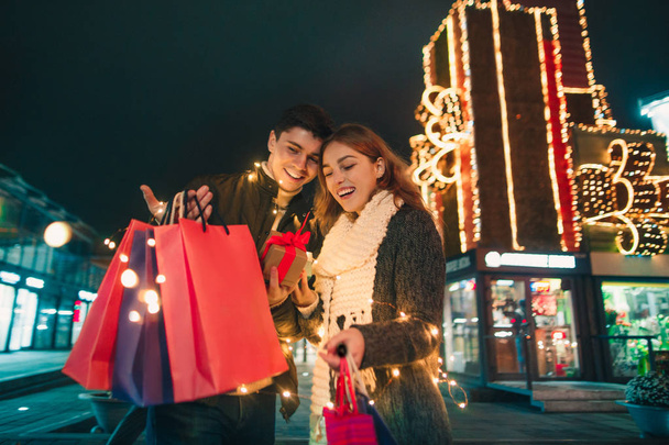 The happy couple with shopping bags enjoying night at city background - Valokuva, kuva