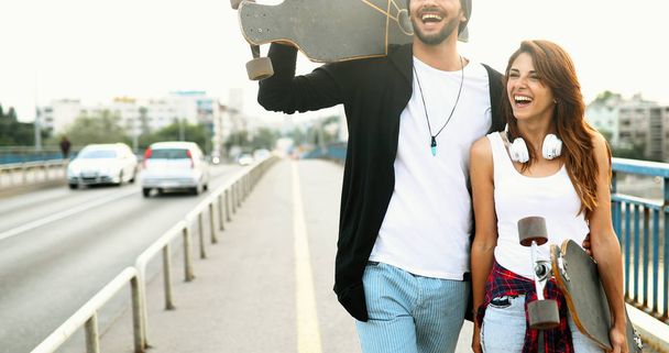  attractive couple carrying skateboards - Foto, imagen