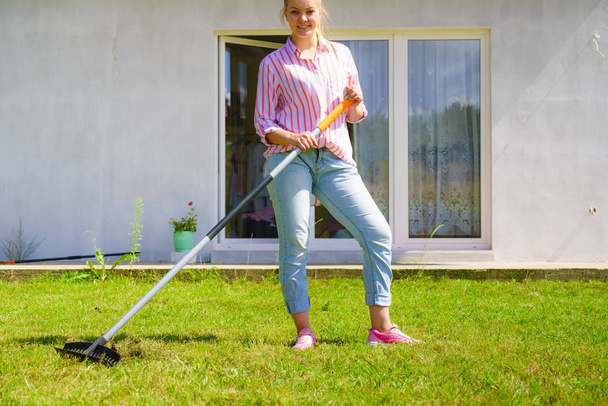 Woman using rake to clean up garden - Foto, Imagem