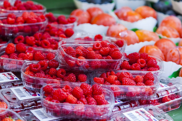 Fresh raspberry in boxes is laid out on a counter of shop - Foto, Imagem