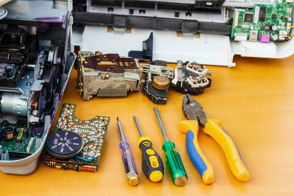 auf dem Desktop sind zerlegte Geräte und Werkzeuge zur Reparatur. - Foto, Bild