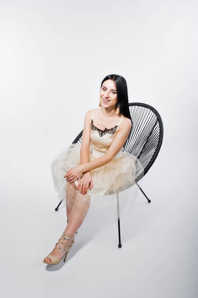 Portrait of brunette girl on beige dress with chair isolated on  - Fotó, kép