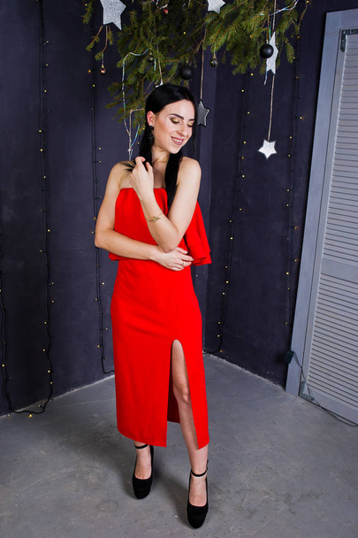 Bruna ragazza in abito rosso posato vicino decorazione nuovo anno in stu
 - Foto, immagini