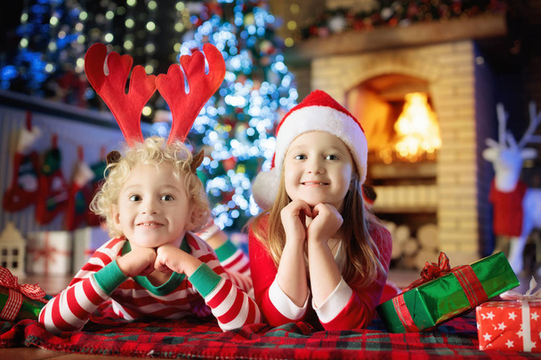 Kind in de kerstboom. Kinderen bij de open haard op Xmas - Foto, afbeelding