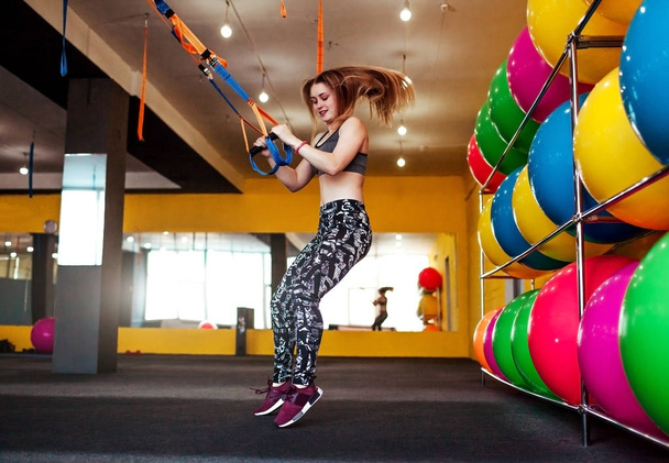 schöne athletische Frau macht Übungen mit Trx in Sportbekleidung im Fitnessstudio - Foto, Bild