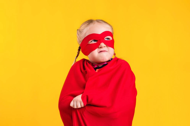 Zabawny moc superbohatera dziecko dziewczynka w czerwony płaszcz i maski. Koncepcja superbohatera. - Zdjęcie, obraz