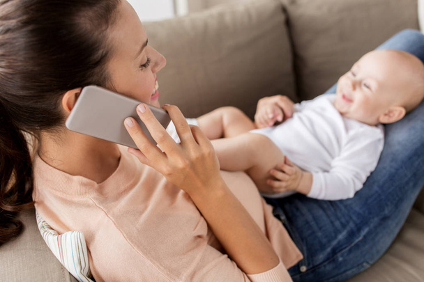 mother with baby calling on smartphone at home - Foto, imagen