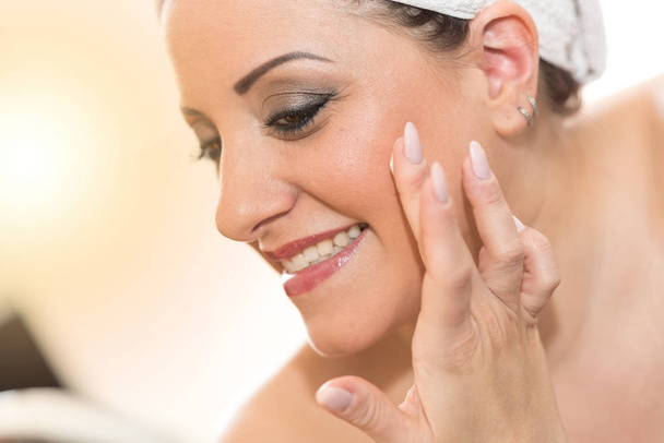 Portrait of smiling young woman applying moisturizing cream - Foto, immagini