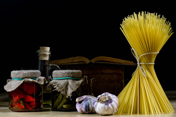 Pasta en olijfolie op een oude keukentafel. Recepten in oude boek - Foto, afbeelding