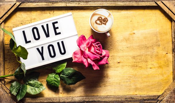 Composition vue du dessus salutation pour la Saint-Valentin pour une femme avec une tasse de cappuccino avec le cœur, une rose et un cadre de mot avec amour Vous notez
 - Photo, image