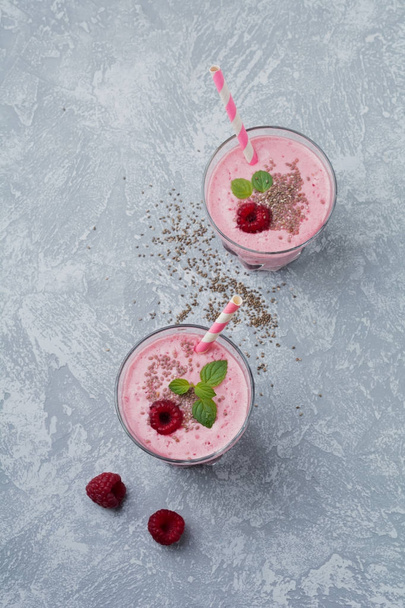 Raspberry smoothie with chia seeds and mint in a glass cup on a gray light stone or concrete background. - Foto, immagini