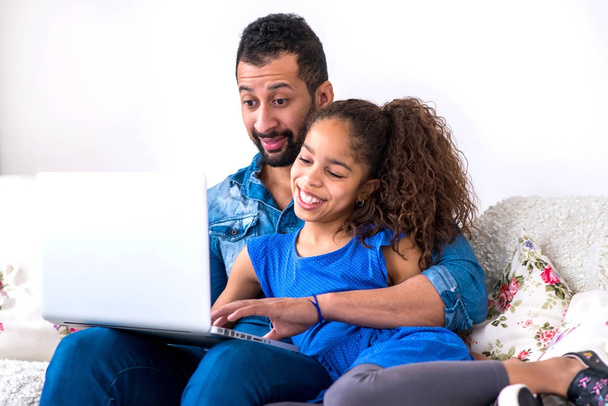 Black father and his daughter siting on a couch with a laptop - Φωτογραφία, εικόνα