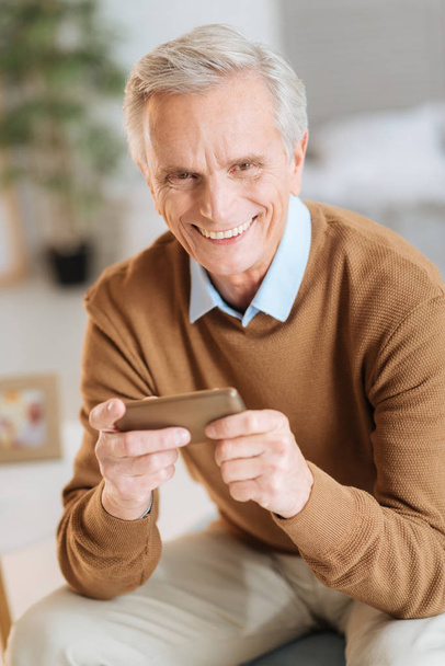 Excited senior man laughing while holding smartphone - Foto, Bild