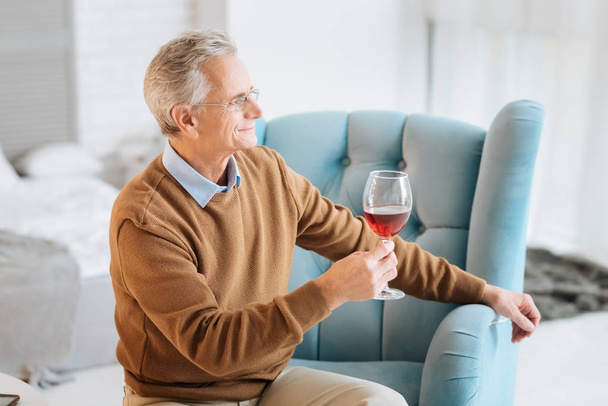 Расслабленный пожилой джентльмен наслаждается красным вином и улыбается
 - Фото, изображение
