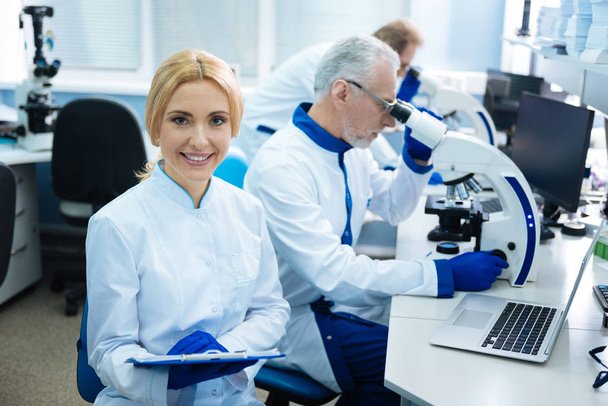 Nice happy scientist working with others in the lab - Фото, изображение
