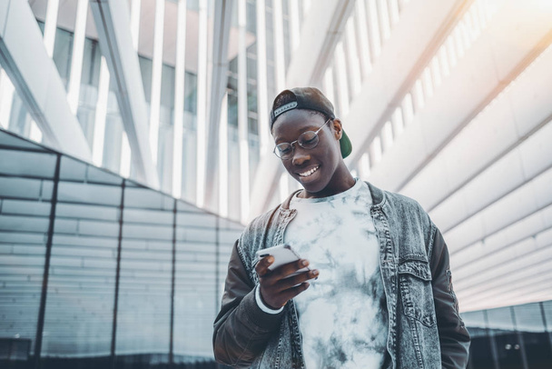 Чорний хлопець вводить повідомлення на свій мобільний телефон
 - Фото, зображення