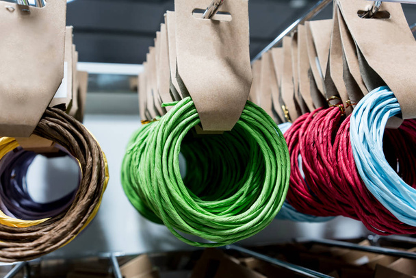 Rows of multicolor paper rope hanging on rack for wholesale stor - Photo, Image