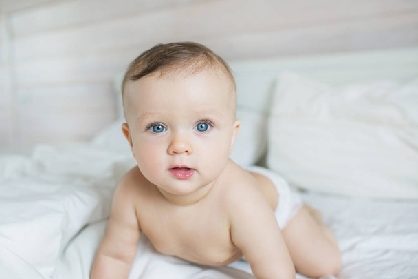 Portrait of pretty caucasian little baby plays on a bed at home - Foto, afbeelding