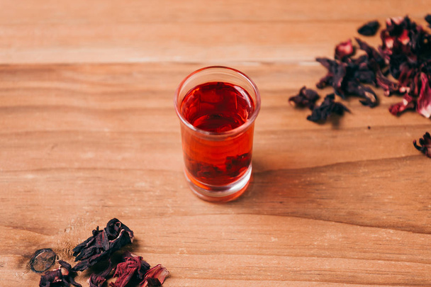 Red hot hibiscus tea in a glass mug on a wooden table - Φωτογραφία, εικόνα