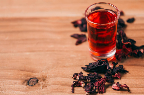 Red hot hibiscus tea in a glass mug on a wooden table - Fotografie, Obrázek