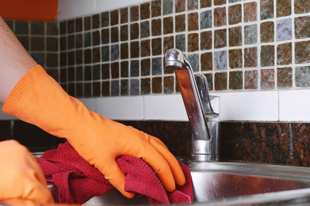 Hand with gloves wiping stainless steel sink with cloth - Photo, image