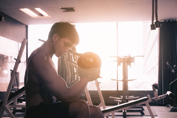 Asain man lifting dumbbell at gym. - Photo, Image
