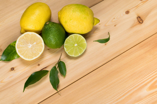 yellow lemon and green lime on a light wooden background - 写真・画像