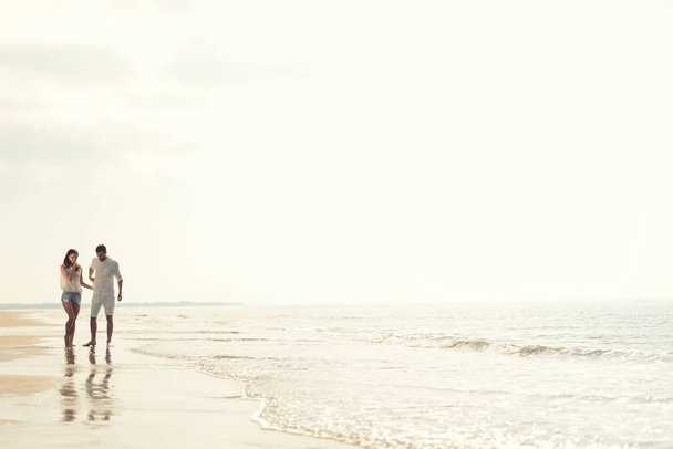 Happy fun beach vacations couple walking together laughing having fun on travel destination. - 写真・画像