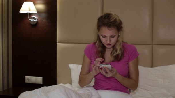 A woman in the bed writes a message on the smartphone. - Séquence, vidéo