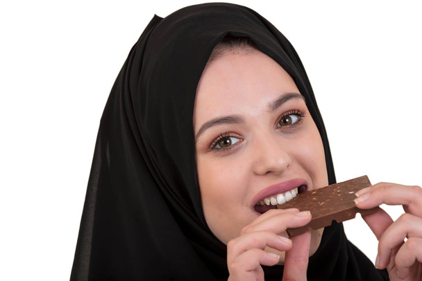 Lovely smiling muslim woman with hijab eating chocolate isolated on white background. - Photo, Image