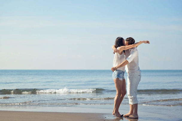 Romantic young couple on the beach kissing. - Фото, зображення