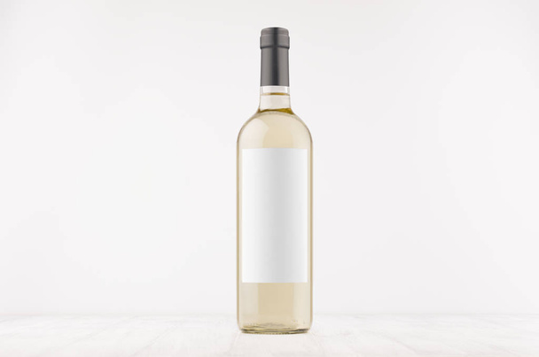 Transparent white wine bottle with blank white label on white wooden board, mock up.  - 写真・画像
