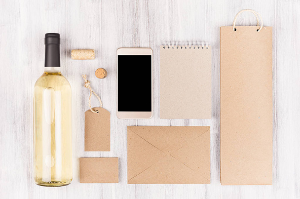 Corporate identity template for wine industry,  blank beige kraft packaging, stationery, phone set with bottle white wine on soft white wood background.  - Fotografie, Obrázek